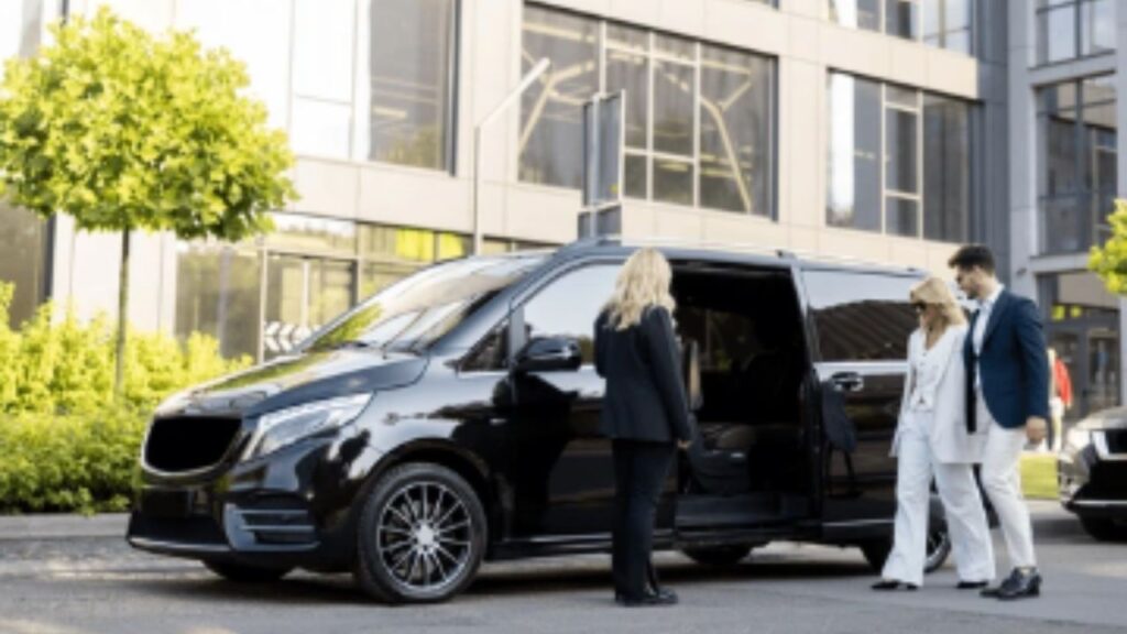 A female chauffeur welcomes a couple into a luxury shuttle