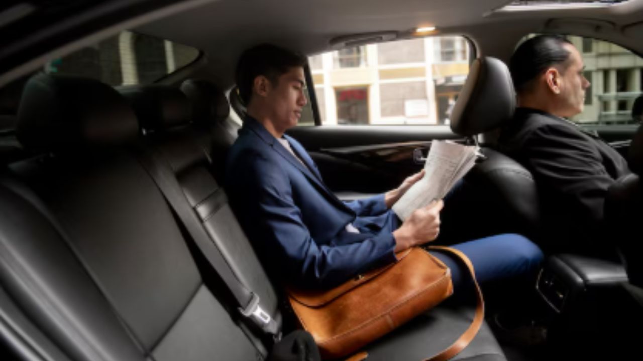 A man in a suit is seated in the back of a luxury shuttle.
