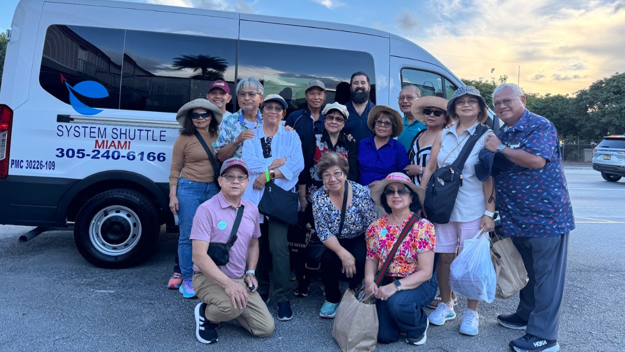 Group of travelers posing and smiling in front of a System Shuttle Miami shared shuttle