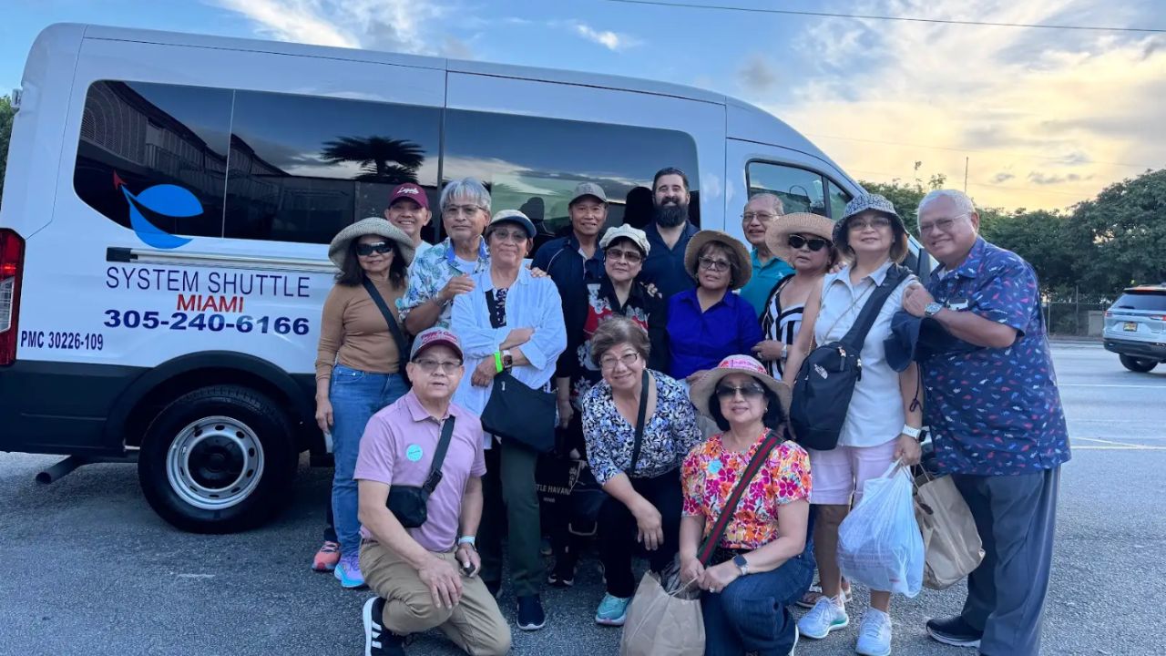 Group of passengers posing together in front of a System Shuttle Miami van