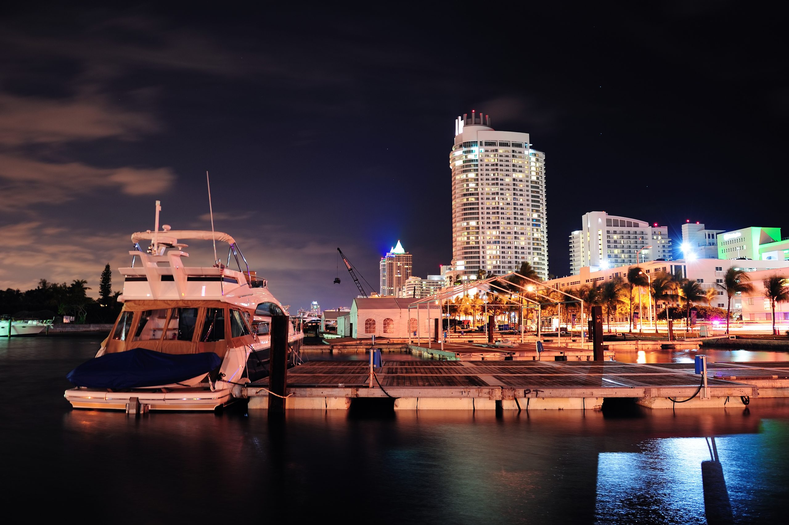 Miami marina at night with yachts and illuminated skyline reflections