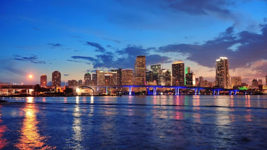 Miami skyline at sunset with city lights reflecting on the water