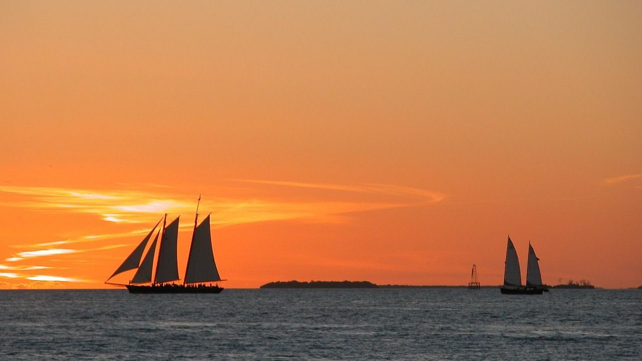 Sailboats gliding across the ocean during a colorful Key West sunset.