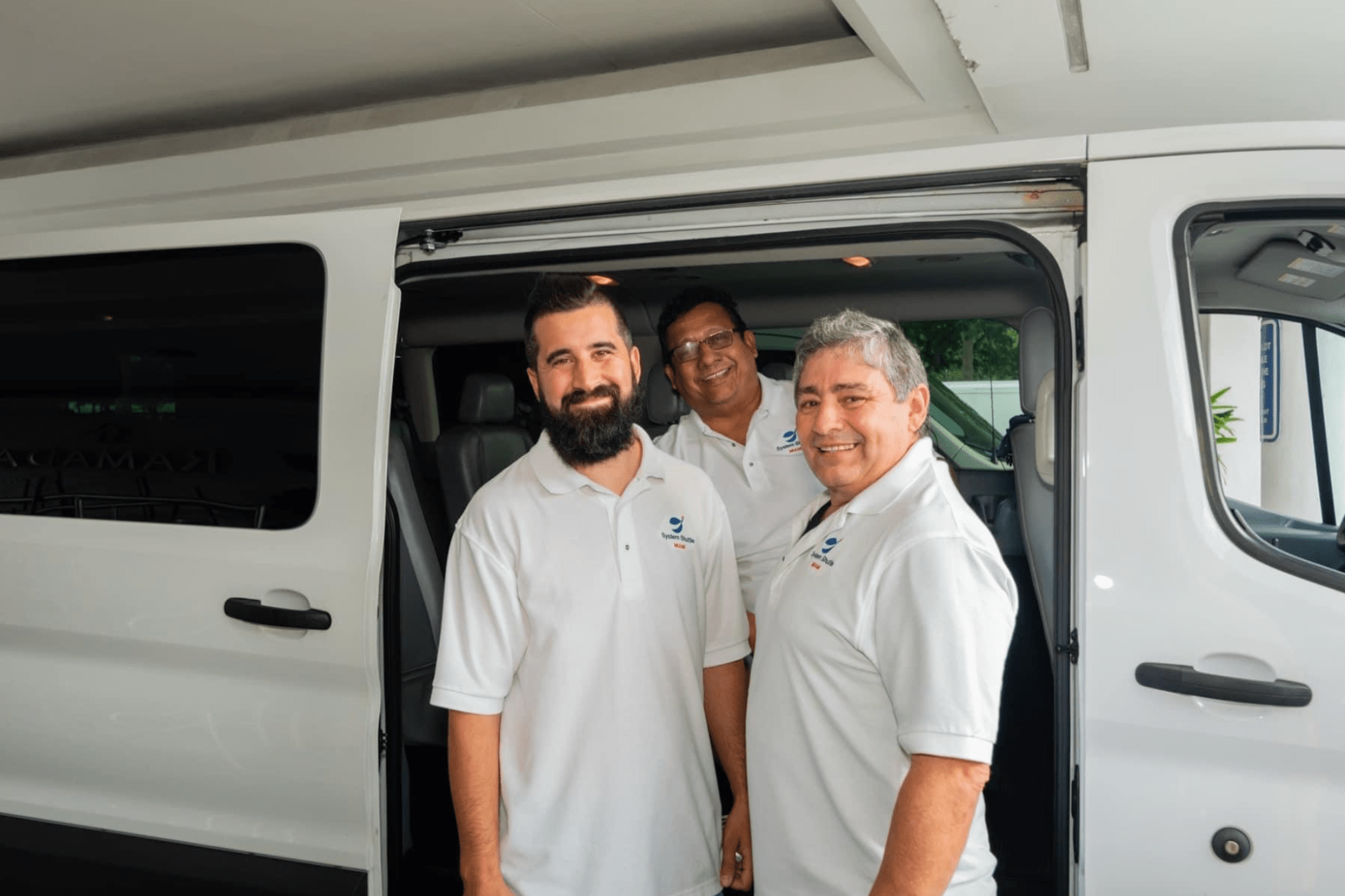 System Shuttle Miami team beside passenger van.