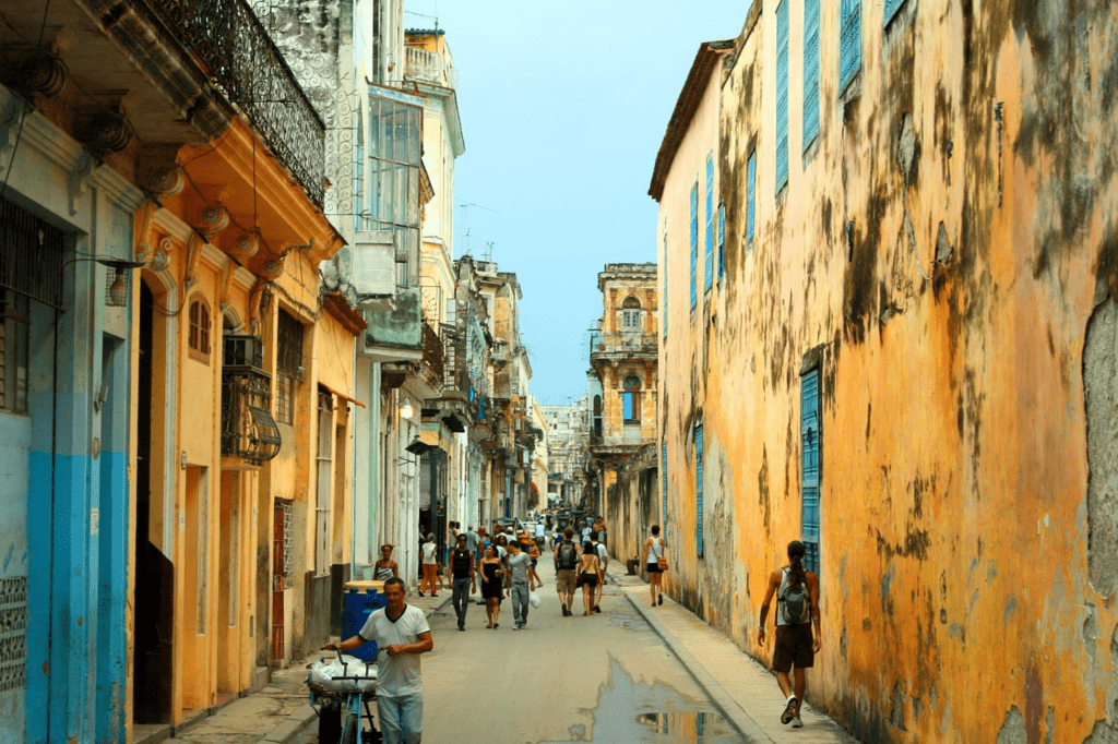 Colorful street in Old Havana with historic buildings, pedestrians, and classic Cuban architecture