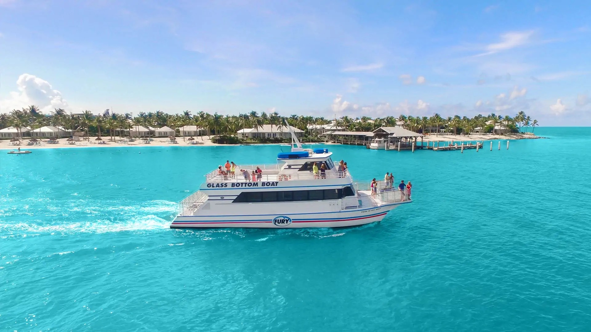 Glass-bottom boat cruising through turquoise waters near Bimini in the Bahamas on a sunny day.