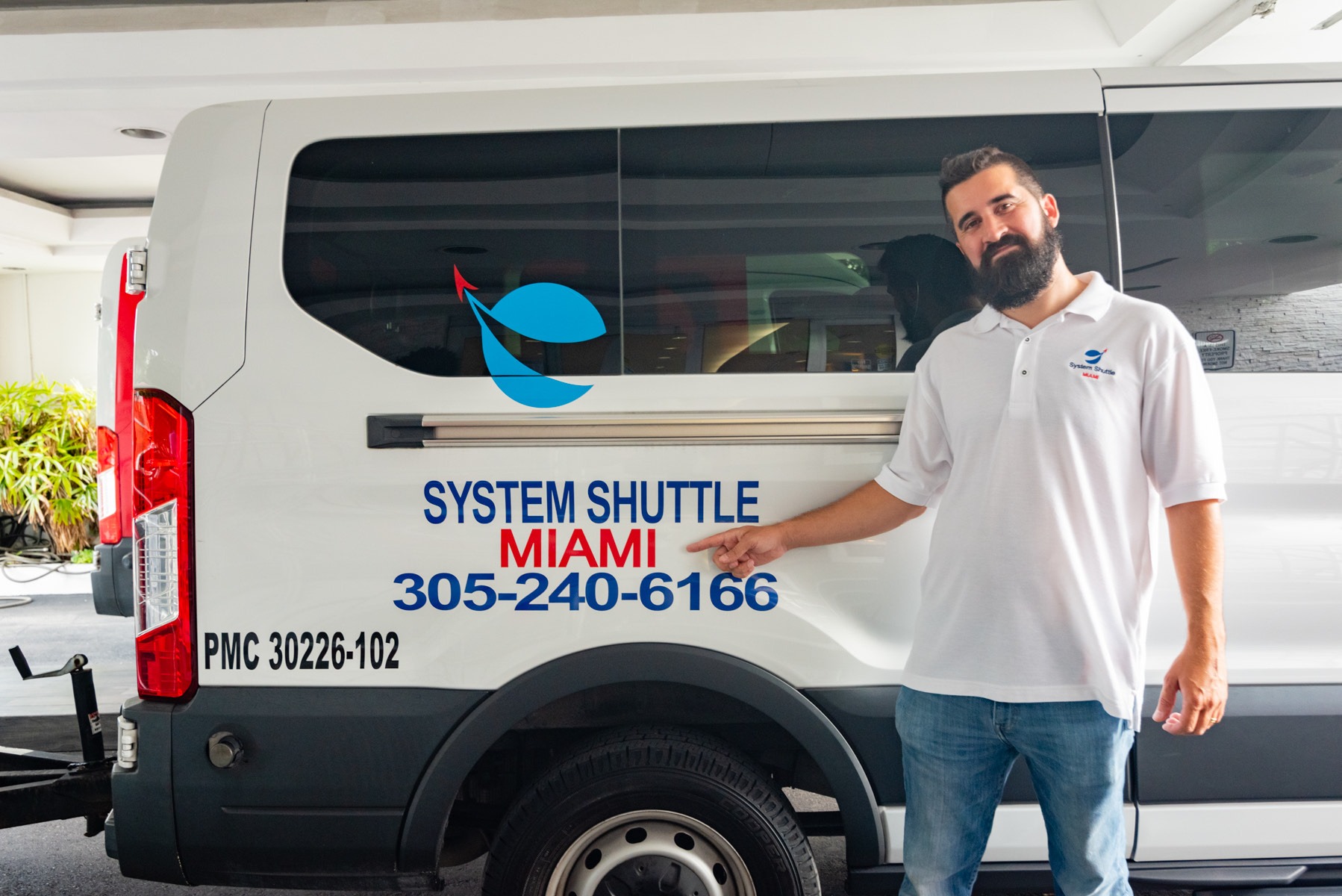 System Shuttle Miami team member standing beside a branded shuttle van