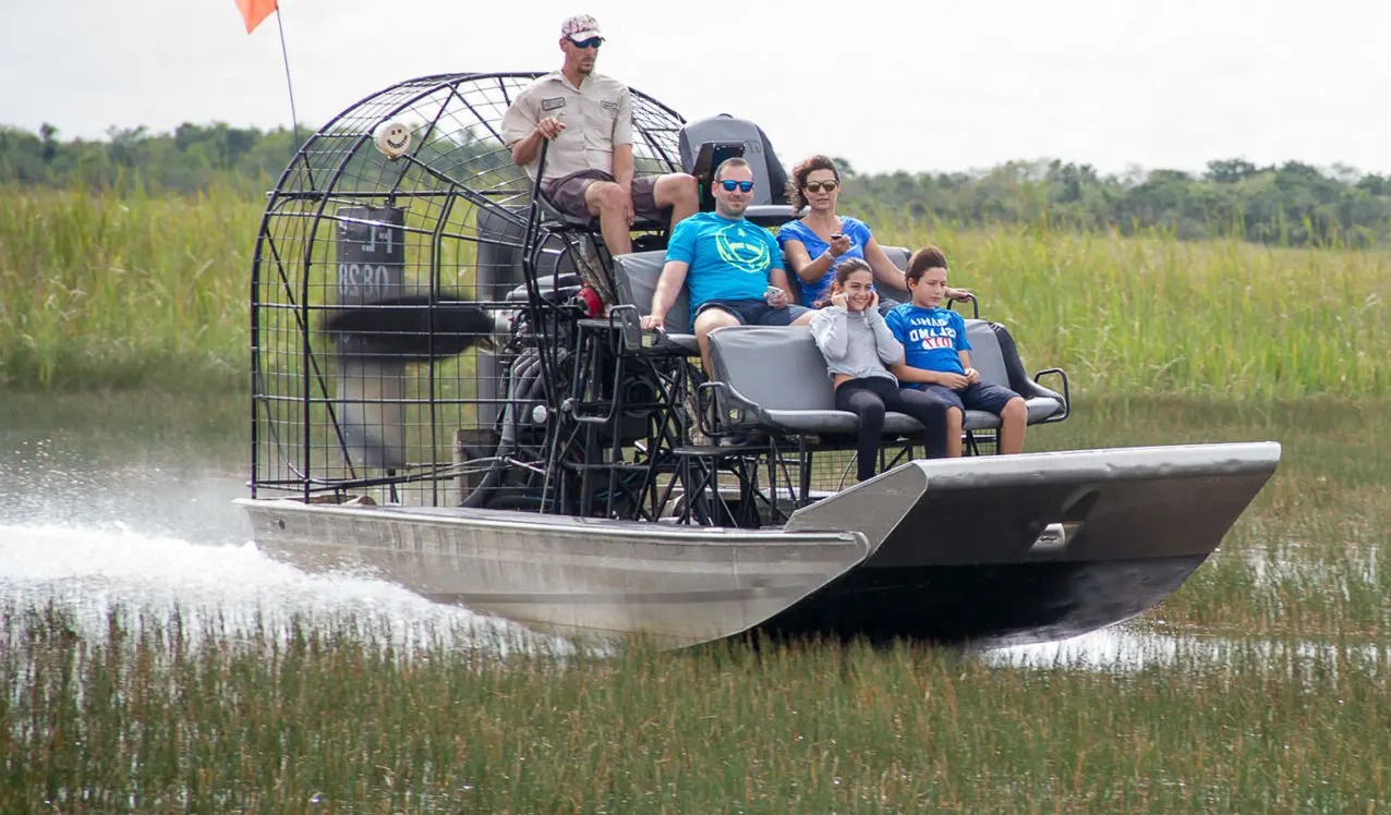 Family enjoying an exciting Everglades airboat tour through the Miami’s wetlands with a professional guide.
