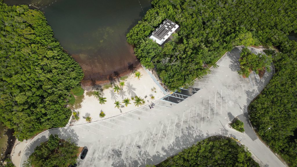 Aerial view of a tropical waterfront parking area surrounded by lush greenery