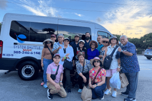 Tour group posing beside a System Shuttle Miami passenger van.