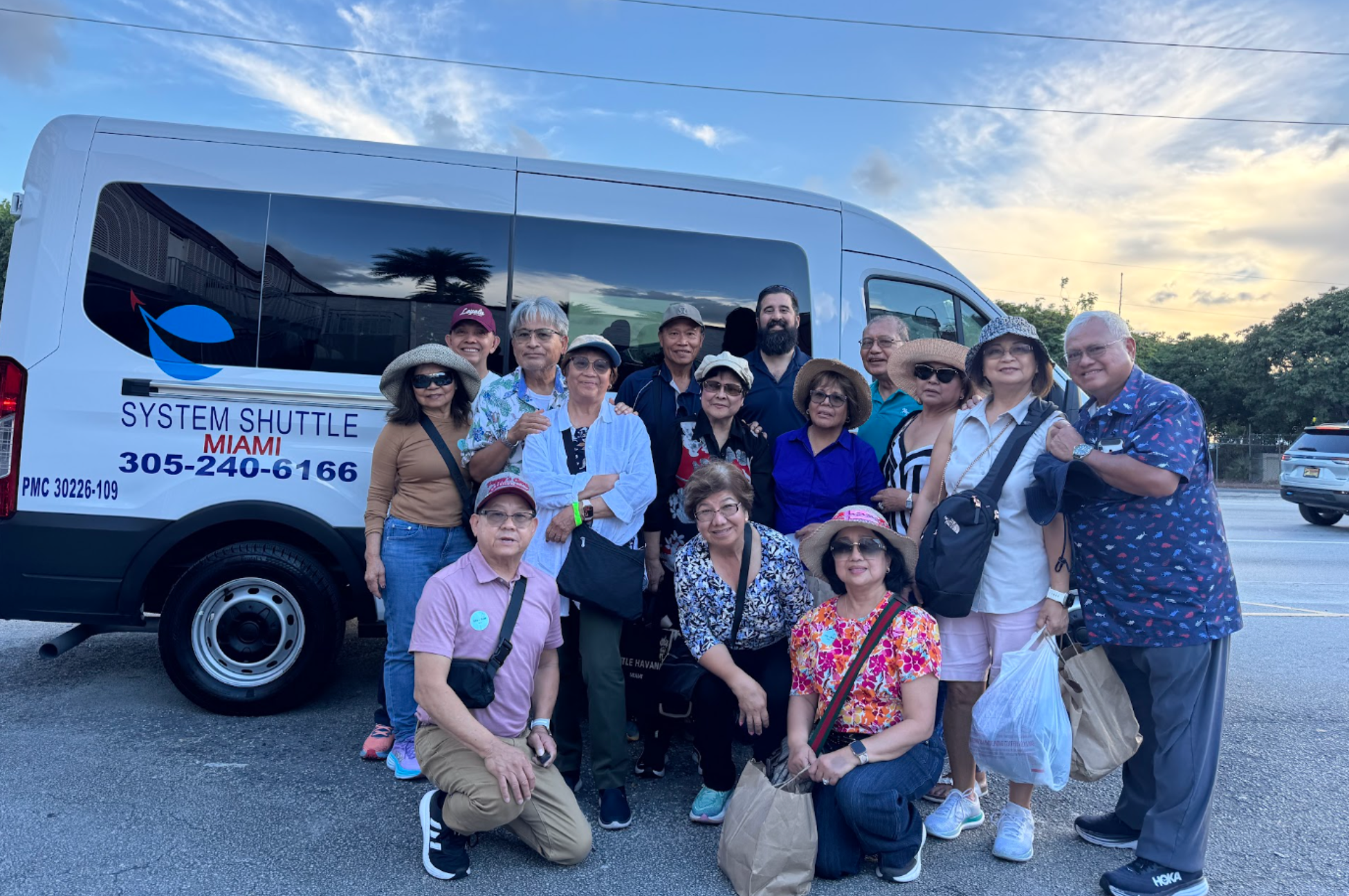 Tour group posing beside a System Shuttle Miami passenger van.