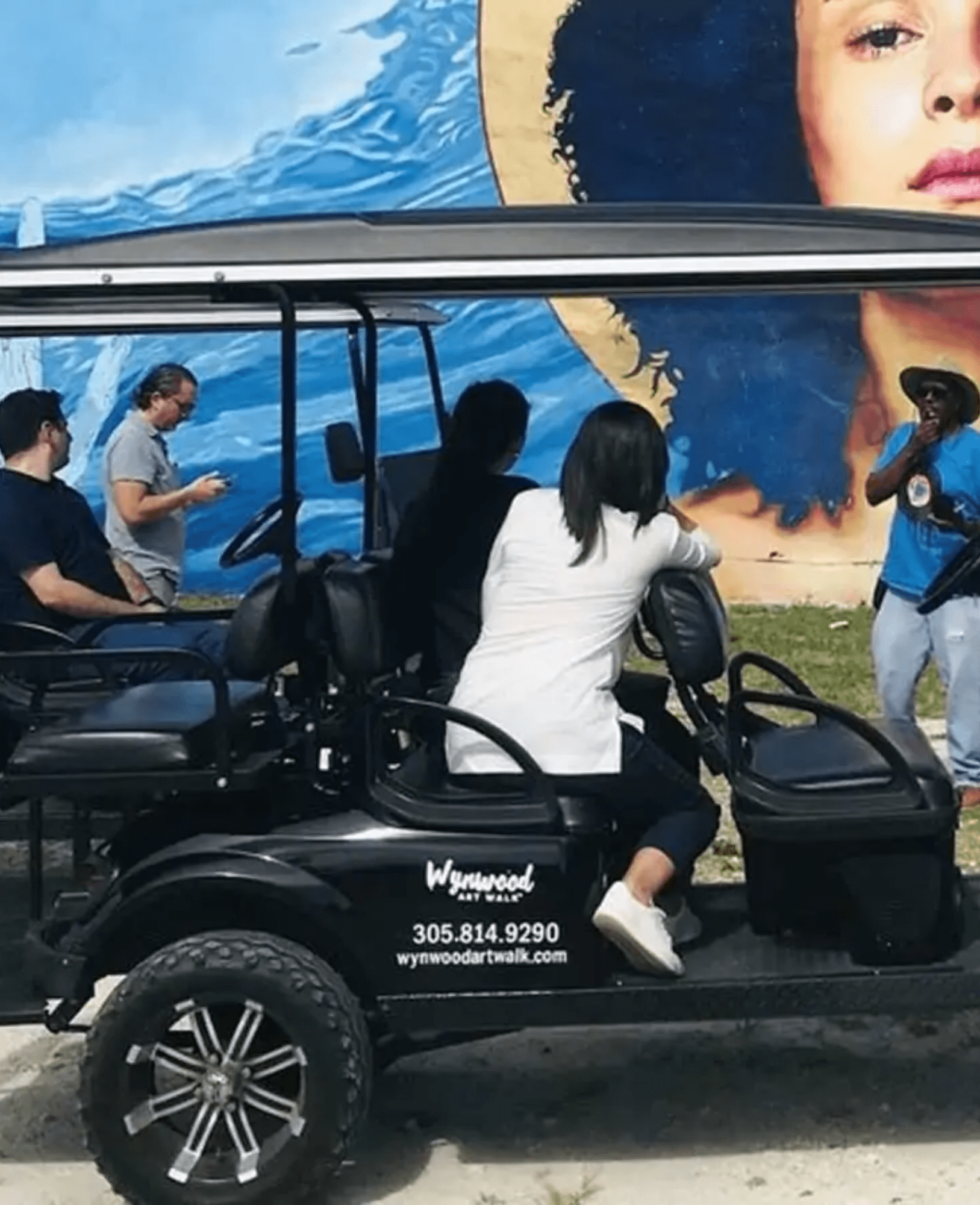 Visitors enjoying a guided Wynwood Art Walk tour beside a colorful Miami mural.