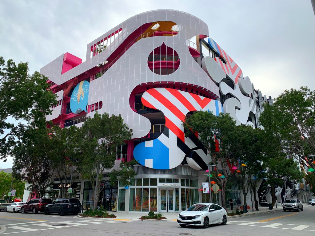Modern building exterior featuring vibrant public art and street-level shopfronts at Miami Design District